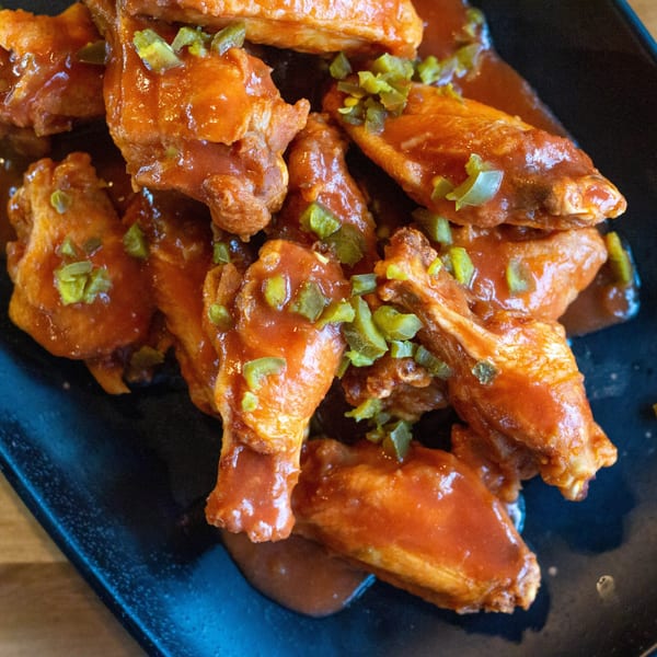 Close-up of Nasty's Sports Bar & Restaurant's chicken wings, coated in orange sauce and topped with jalapeños.