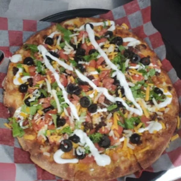 A Nasty's Sports Bar & Restaurant taco pizza with lettuce, tomatoes, olives, and sour cream.